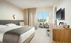 Moderni hotellihuone, jossa on parivuode, istuinalue ja kalustettu parveke. (Tekoälyn luoma teksti)