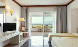 Hotellihuoneen sisätila, jossa kaksi vuodetta, kirjoituspöytä ja terassi näkymällä merelle. (Tekoälyn luoma teksti)