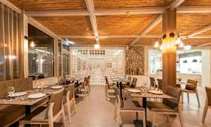 Ravintolan sisustus, jossa katettuja pöytiä ja tuoleja. (Tekoälyn luoma teksti)