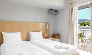 Hotellihuone, jossa on kaksi erillistä vuodetta, korilaukku ja parveke näkymillä. (Tekoälyn luoma teksti)