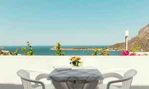 Näkymä merelle parvekkeelta, jossa on pöytä, kaksi tuolia ja kukkavaasi. (Tekoälyn luoma teksti)