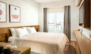 Hotellihuone, jossa parivuode, seinäkoristelu ja lasiovi, joka johtaa parvekkeelle. (Tekoälyn luoma teksti)