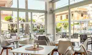 Valoisa ravintola, jonka ikkunat avautuvat kadulle ja ulkopöydille. (Tekoälyn luoma teksti)