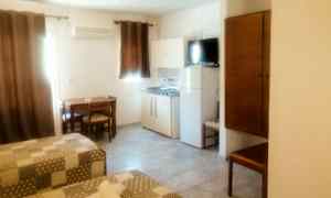 Huone, jossa kaksi sänkyä, pöytä tuoleineen, kaappi ja keittokomero. (Tekoälyn luoma teksti)