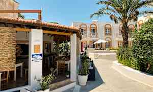 Rakennus, jossa on terassi, palmupuita ja avoin baari. (Tekoälyn luoma teksti)