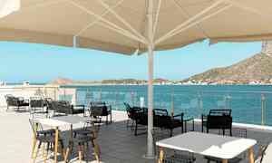 Ulkoterassi pöytineen ja tuoleineen suuren aurinkovarjon alla, näkymä merelle ja ympäröiville mäille. (Tekoälyn luoma teksti)