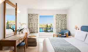 Hotellihuone, jossa parveke ja huonekalut, kuten sänky, kirjoituspöytä, tuoli ja nojatuoli. (Tekoälyn luoma teksti)