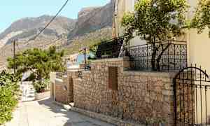 Kivimuuri, jossa portti ja puita, taustalla vuori. (Tekoälyn luoma teksti)