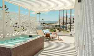 Terassi, jossa poreallas, aurinkotuoleja ja näkymä palmuihin ja rakennuksiin taustalla. (Tekoälyn luoma teksti)