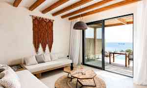 Modernisti sisustettu olohuone, josta on näkymä merelle lasiovesta. (Tekoälyn luoma teksti)