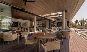 Avoimia istumapaikkoja, joissa puiset pöydät ja punotut tuolit katon alla. (Tekoälyn luoma teksti)