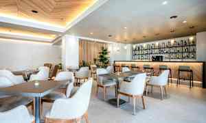 Nykyaikainen ja valoisa kahvila, jossa on pöytiä ja tuoleja sekä hyvin varusteltu baaritiski. (Tekoälyn luoma teksti)