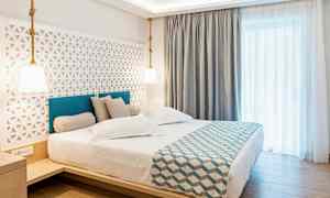 Hotellihuone, jossa on parivuode, tyylikäs sisustus ja vaaleat verhot. (Tekoälyn luoma teksti)