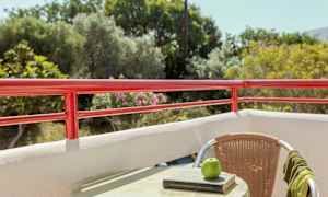 Näkymä parvekkeelta, jossa on punaista kaidetta, kaluste, kirja ja omena pöydällä. (Tekoälyn luoma teksti)