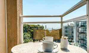 Parveke merinäköalalla. Pöydällä on kaksi kahvikuppia ja astia sokeritikkuja varten. (Tekoälyn luoma teksti)