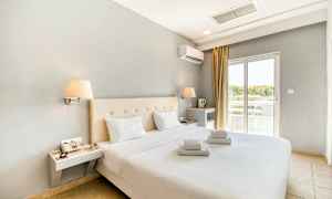 Modernisti sisustettu hotellihuone, jossa parivuode ja valkoiset lakanat. Ikkuna tuo valoa. (Tekoälyn luoma teksti)