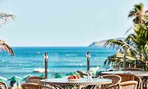 Näkymä pöydän yli, jolla on juomia ja hedelmiä, kohti merta. (Tekoälyn luoma teksti)