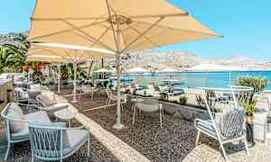 Terassi, jossa istuimia ja aurinkovarjoja meren äärellä. (Tekoälyn luoma teksti)