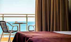 Huone, jossa ruskeat verhot, näkymä merelle ja kalustettu parveke. (Tekoälyn luoma teksti)