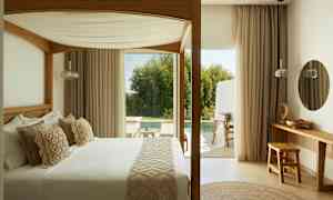 Makuuhuone, jossa on pylvässänky ja näkymä terassille ja uima-allasalueelle. (Tekoälyn luoma teksti)