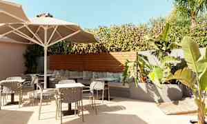 Ulkoilma istuma-alue, jossa pöytiä, tuoleja ja kasveja. (Tekoälyn luoma teksti)