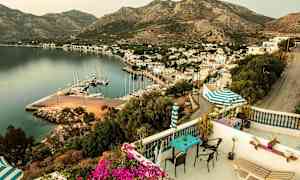 Näköala parvekkeelta satamaan, jonka ympärillä on veneitä, rakennuksia ja vuoria taustalla. (Tekoälyn luoma teksti)