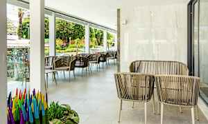 Ulkokalusteet, joissa on rottinkituoleja ja pöytiä terassilla, kasveja ja näkymä kadulle. (Tekoälyn luoma teksti)