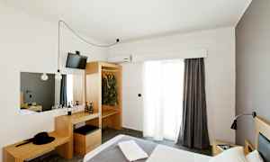 Hotellihuone, jossa on sänky, vaatekaappi ja kirjoituspöytä. (Tekoälyn luoma teksti)