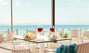 Kuva ulkoilmaravintolasta katetulla pöydällä, näkymä merelle. (Tekoälyn luoma teksti)