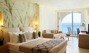 Hotellihuone merinäköalalla ja modernilla sisustuksella, mukaan lukien sänky, sohva ja parveke. (Tekoälyn luoma teksti)