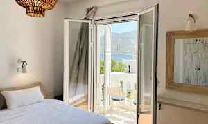 Huone, jossa sänky, avoin parvekkeen ovi ja näkymä vuoristoiseen maisemaan. (Tekoälyn luoma teksti)