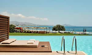 Näkymä uima-altaalta merelle, aurinkotuoleja ja varjoja. (Tekoälyn luoma teksti)