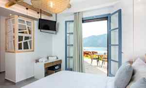 Hotellihuone, jonka avoimet ovet johtavat terassille ja merinäköalaan. (Tekoälyn luoma teksti)