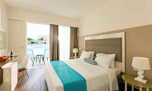 Hotellihuone, jossa on parivuode, yöpöytä, tuoli ja kirjoituspöytä. Ikkunasta näkymä uima-altaalle. (Tekoälyn luoma teksti)