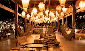 Yöaikainen lounge-alue, jossa roikkuvia valaisimia ja istuimia. (Tekoälyn luoma teksti)