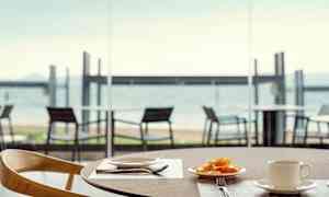 Lautanen hedelmiä ja kuppi pöydällä, näkymä rannalle. (Tekoälyn luoma teksti)