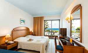 Hotellihuone, jossa on kaksi sänkyä, työpöytä, peili ja parveke näköalalla merelle. (Tekoälyn luoma teksti)