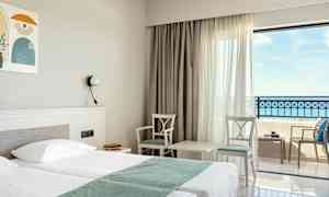 Hotellihuone, jossa parivuode, kaksi tuolia ja pöytä ikkunan äärellä, merinäköala. (Tekoälyn luoma teksti)