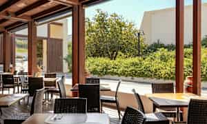 Ulkoilmapatio, jossa on pöytiä ja tuoleja, ympäröitynä vehreydellä. (Tekoälyn luoma teksti)