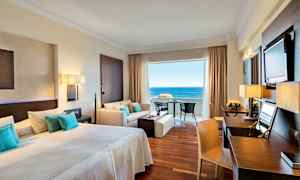 Hotellihuone, jossa parivuode, oleskelutila ja näkymä merelle. (Tekoälyn luoma teksti)