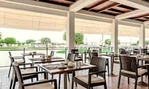 Ulkoterassi, jossa pöytiä ja tuoleja, ympäröivä vehreys. (Tekoälyn luoma teksti)