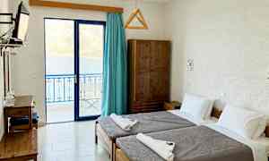 Hotellihuone, jossa kaksi yhden hengen sänkyä ja merinäköala lasiovista. (Tekoälyn luoma teksti)