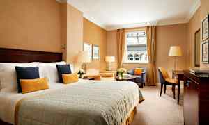 Tyylikäs hotellihuone, jossa iso sänky, oleskelutila ja ikkuna näkymineen. (Tekoälyn luoma teksti)