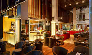 Ravintola, jossa on buffet ja istumapaikkoja, sisustettu puuelementeillä ja lämpimällä valaistuksella. (Tekoälyn luoma teksti)