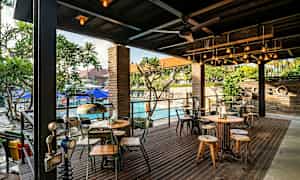 Ulkoterassi, jossa on pöytiä ja tuoleja, ja taustalla uima-allas. (Tekoälyn luoma teksti)