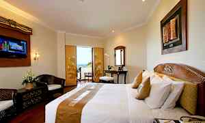 Hotellihuone, jossa on parivuode, kirjoituspöytä, oleskelutila ja parveke, josta on näkymä. (Tekoälyn luoma teksti)