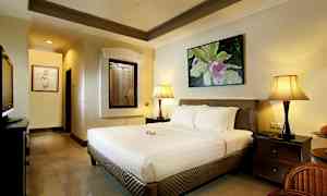 Makuuhuone, jossa on suuri sänky, kaksi yöpöydän lamppua ja koristeellinen taulu seinällä. (Tekoälyn luoma teksti)