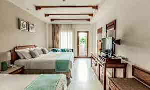 Hotellihuone, jossa on kaksi suurta vuodetta, televisio ja ikkuna, josta tulvii valoa, sekä parveke. (Tekoälyn luoma teksti)