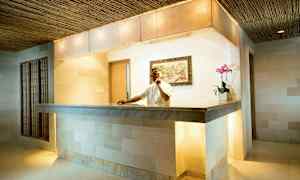 Vastaanottotiski modernissa hotellissa, seinällä koristeellinen maalaus ja koristeena kukkaruukku. (Tekoälyn luoma teksti)