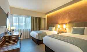 Hotellihuone, jossa on kaksi erillistä sänkyä, kirjoituspöytä ja ikkuna. (Tekoälyn luoma teksti)